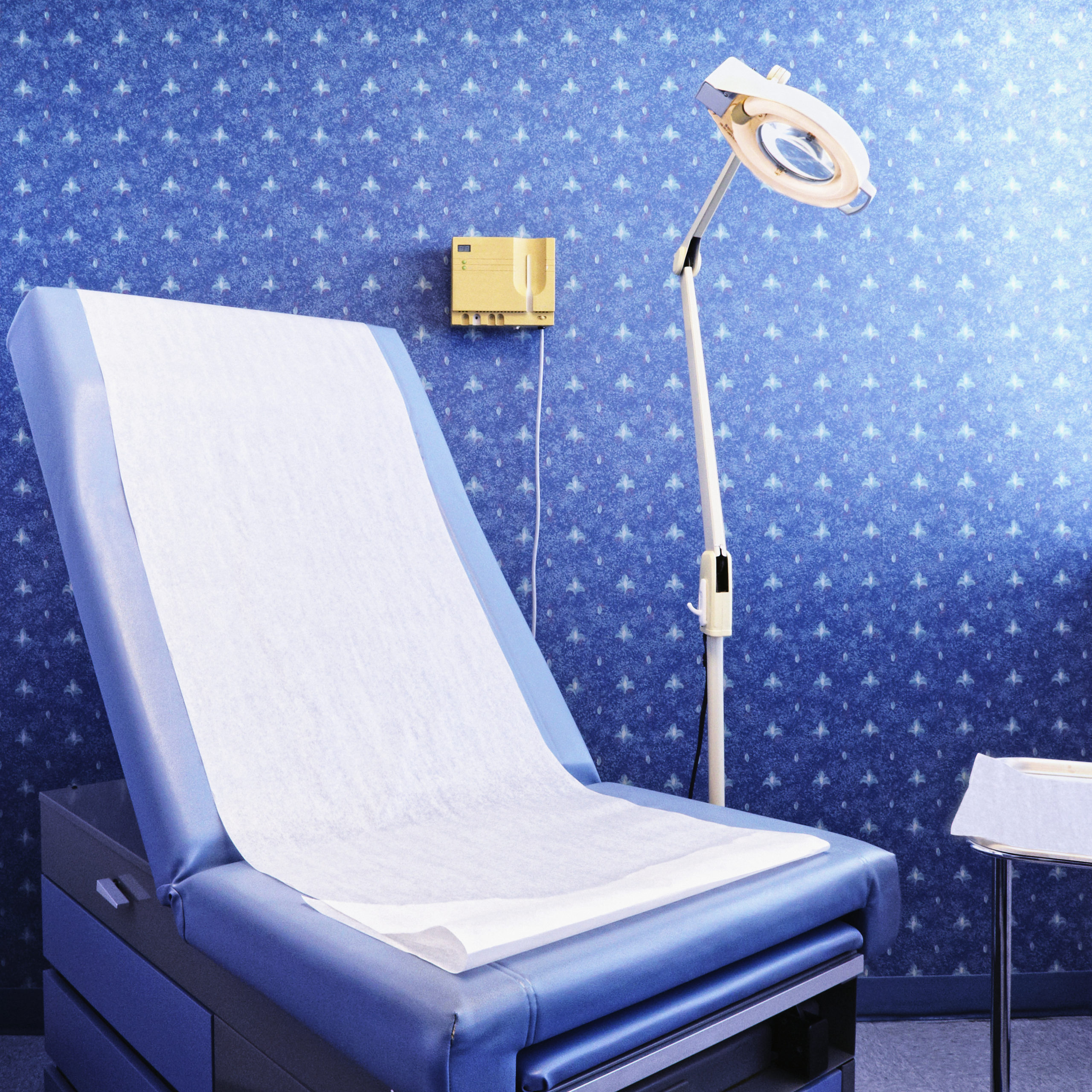 Dermatology examination table and lamp in a healthcare setting.