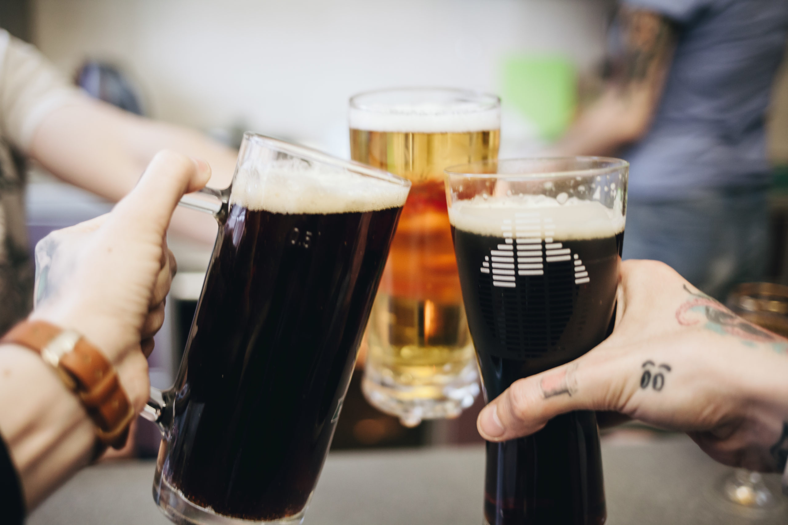 Group toasting with beer mugs at a gentlemen’s club celebrating camaraderie and drinks.