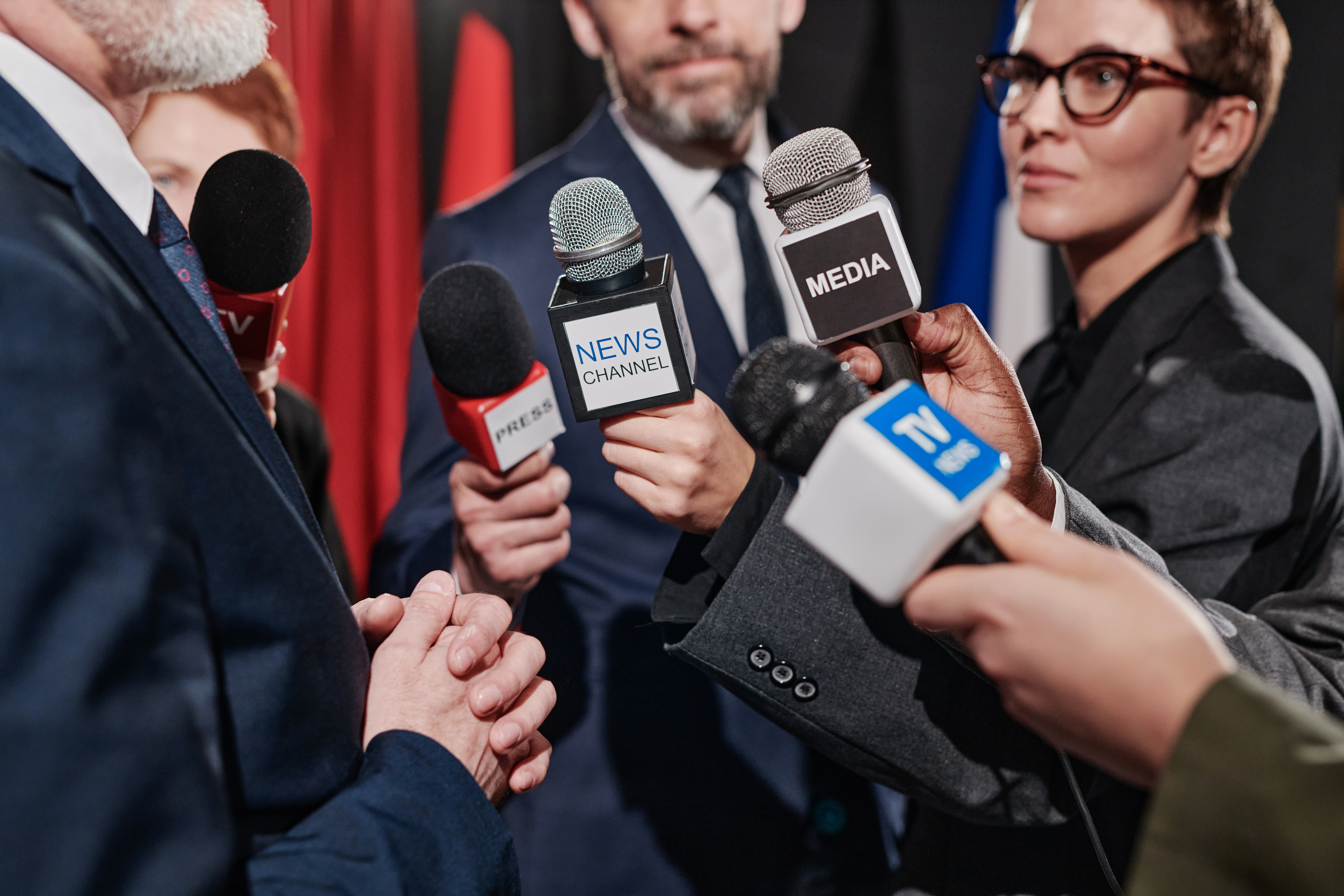 Businessman being interviewed by journalists and media representatives discussing ethics of journalism.