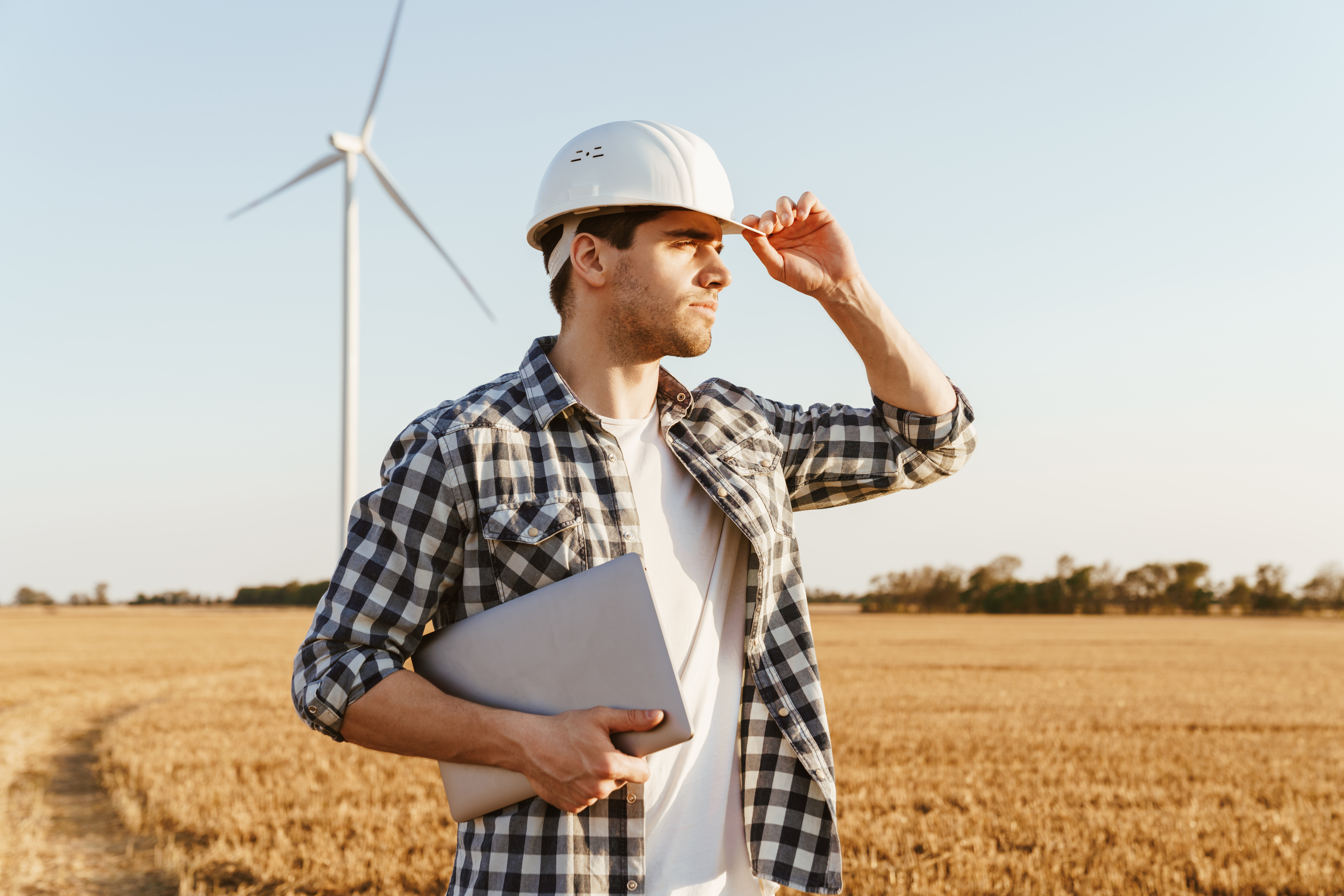 Electrical engineer in field with laptop, planning an electrical business
