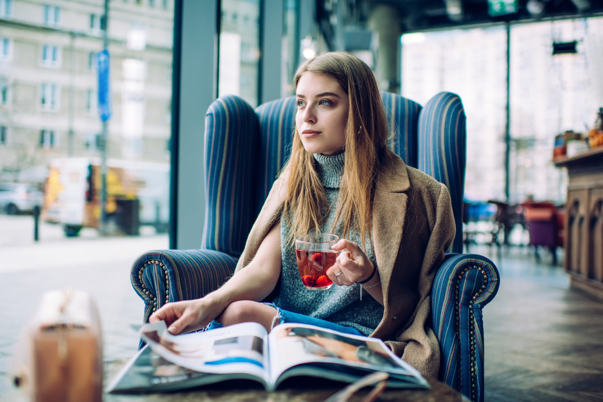 Woman reading magazine in cafe, illustrating The Hunger Games reading guide