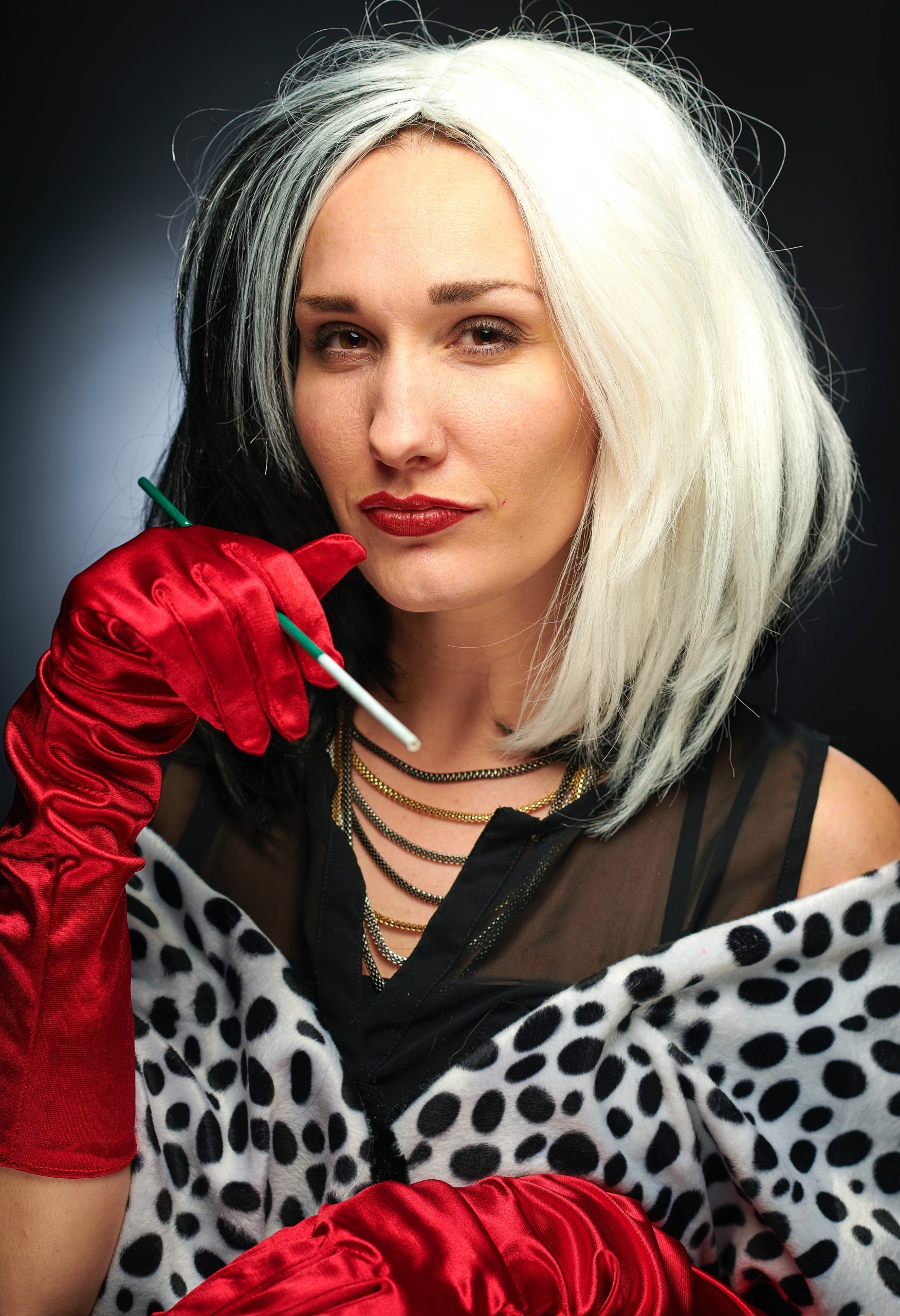 Woman with striking black and white hair and red gloves embracing aging and confidence.