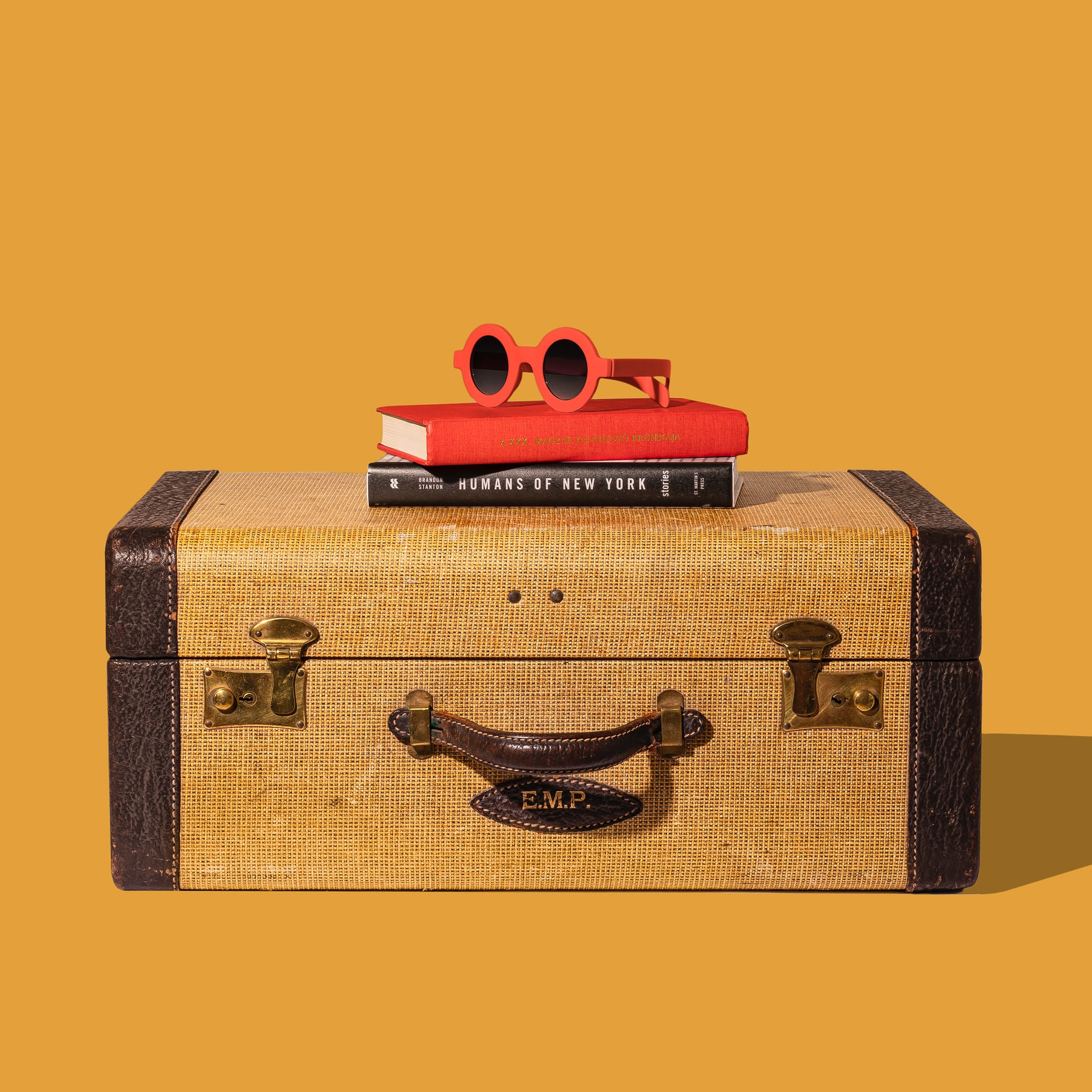 Vintage suitcase with sunglasses and a book for road trip essentials.