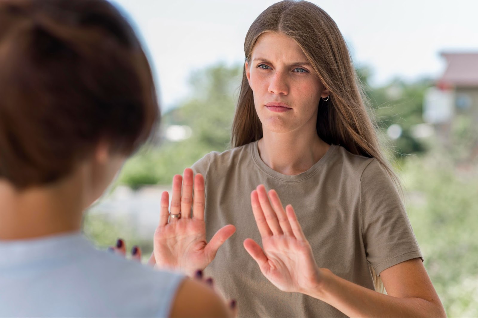 Woman with hand gesture indicating "no" illustrating boundary setting and self-care.