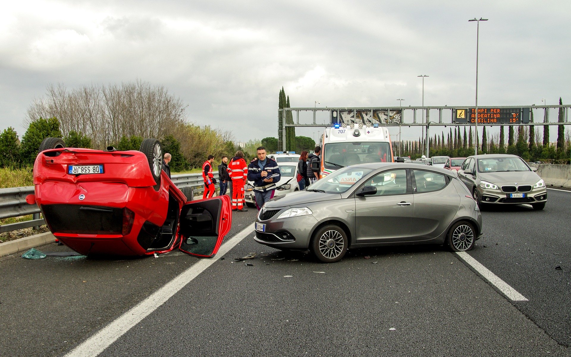 Damaged red car and other vehicles at accident scene with emergency responders